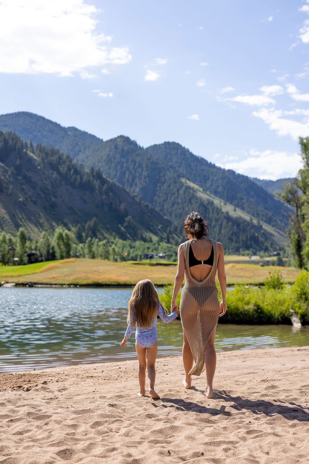 Mom And Daughter On The River Beach