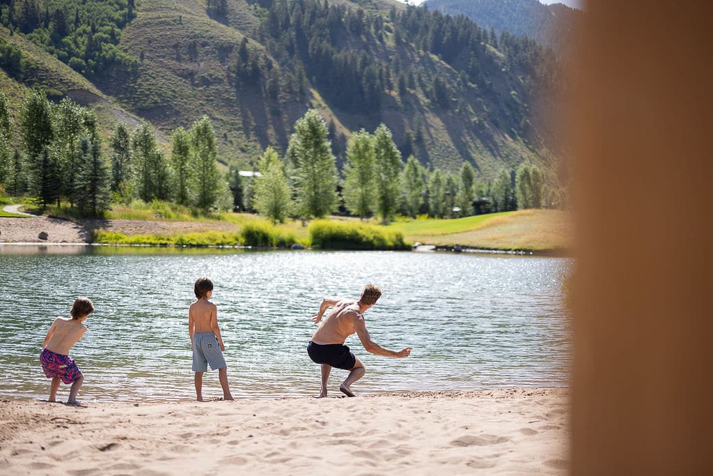 Kids And Dad Playing On The River Beach