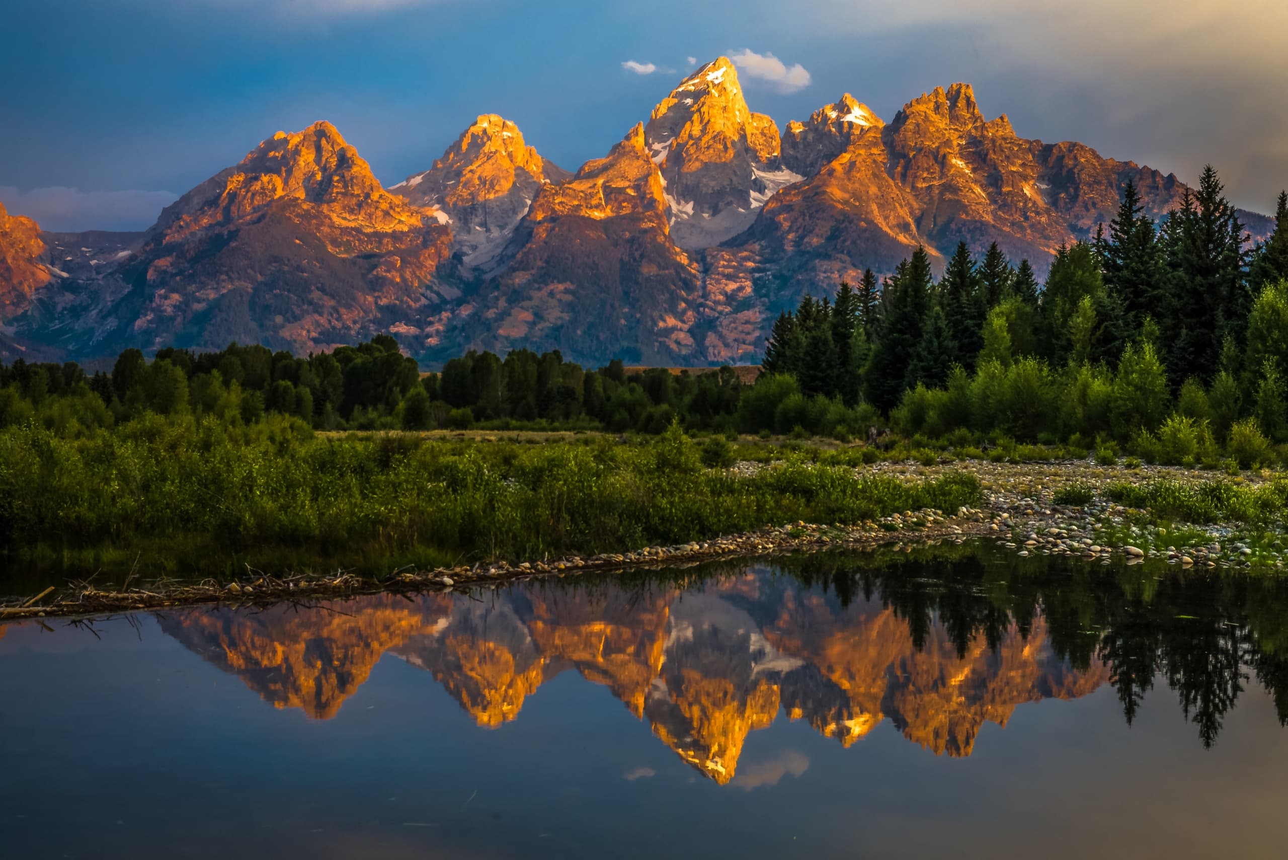 The dramatic colors of the Grand Teton Mountains reflecting in the water on a clear summer morning.
