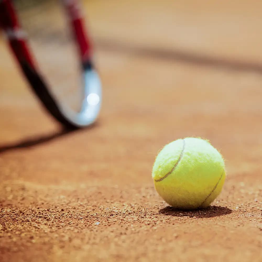 a tennis ball on a red clay court