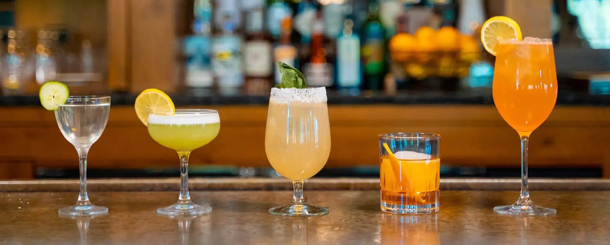 a row of cocktails on a bar top