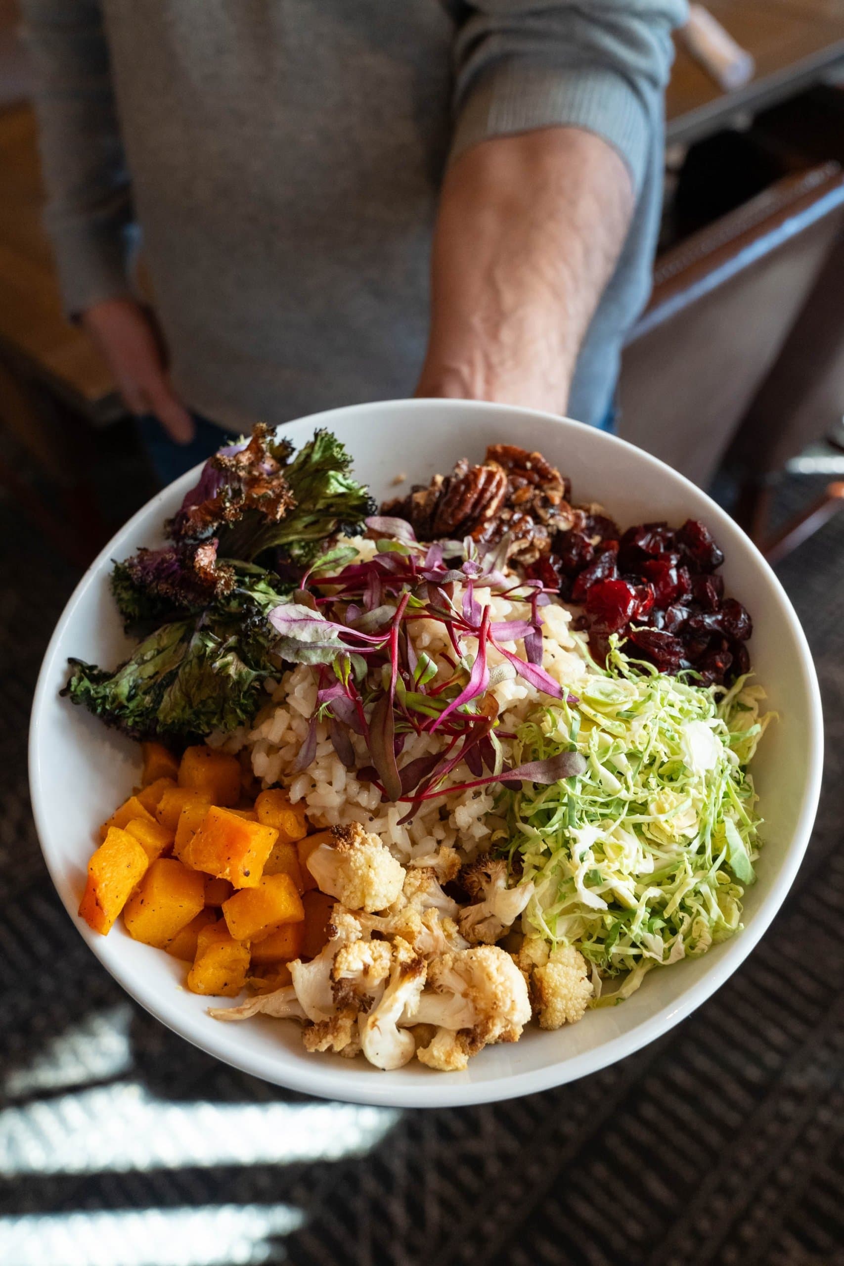 A vegetarian rice bowl being held out in a man's hand