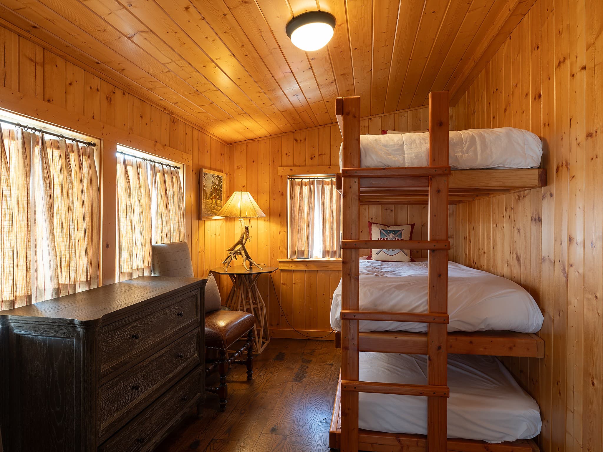 Triple bunk room with knotty pine walls in a family cabin at Snake River Sporting Club in Jackson Hole, Wyoming