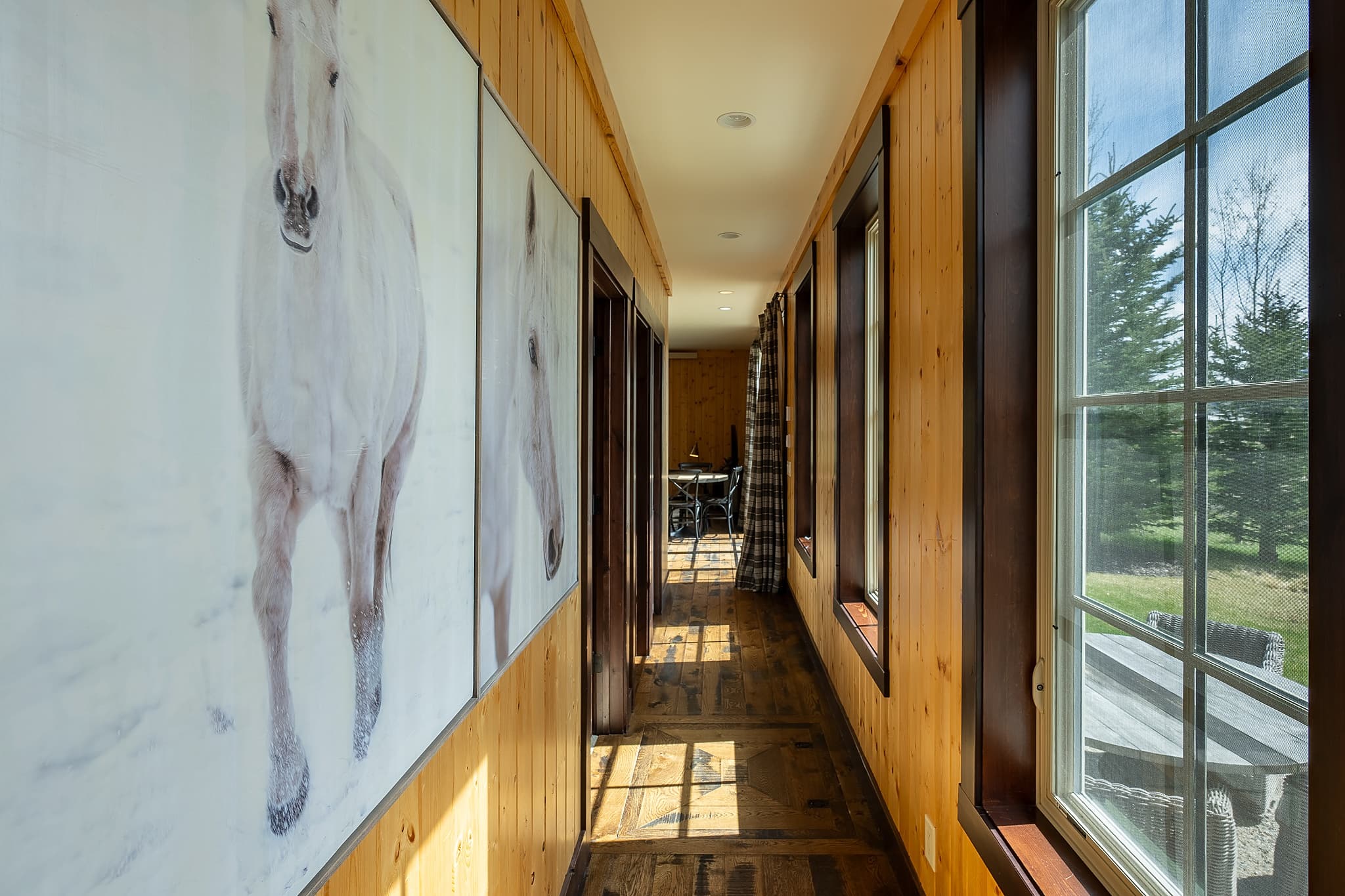 Sunlit cabin hallway with western art at Snake River Sporting Club in Jackson Hole