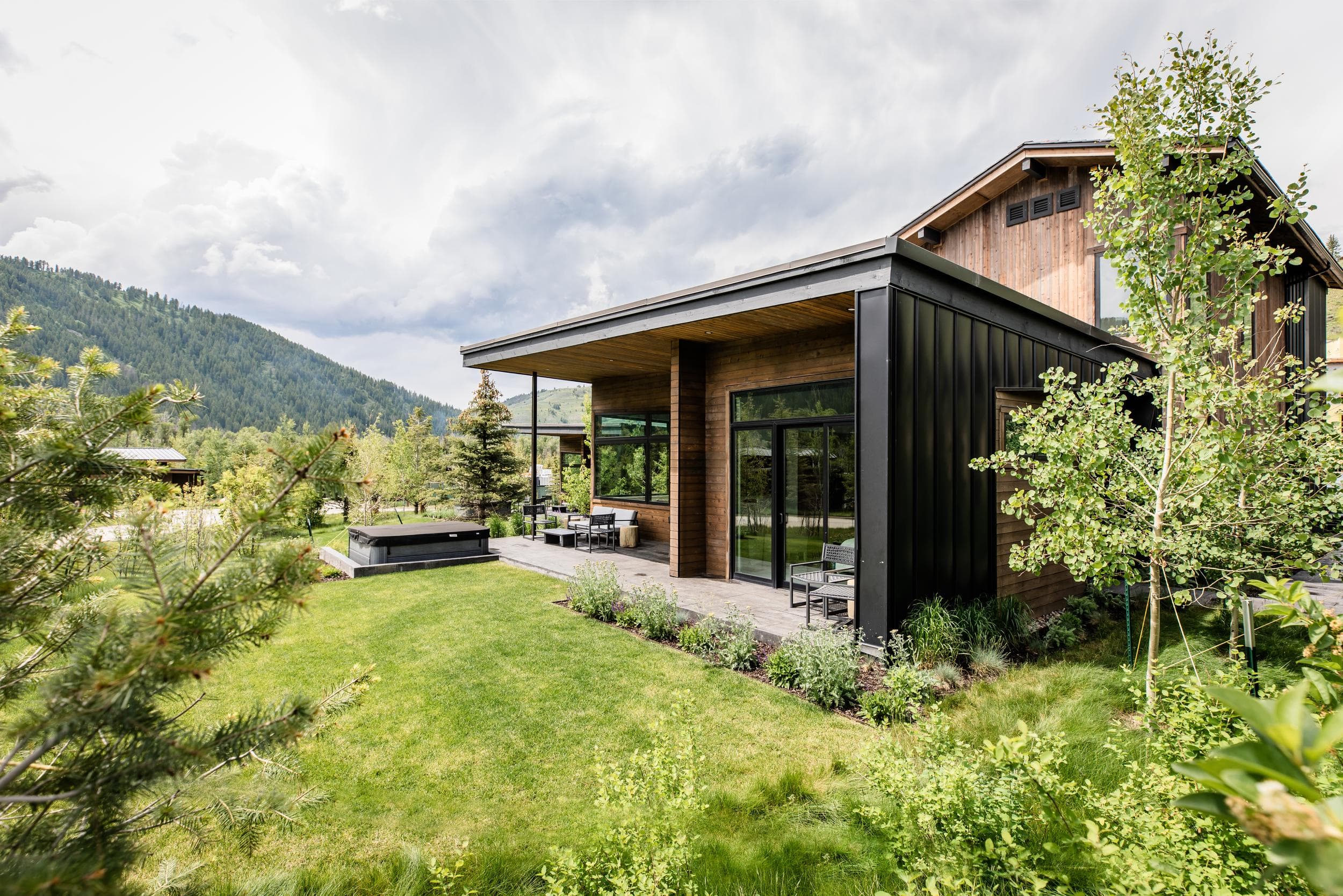 Meadow Cabin with a covered patio, hot tub and green lawn at Snake River Sporting Club in Jackson Hole, Wyoming