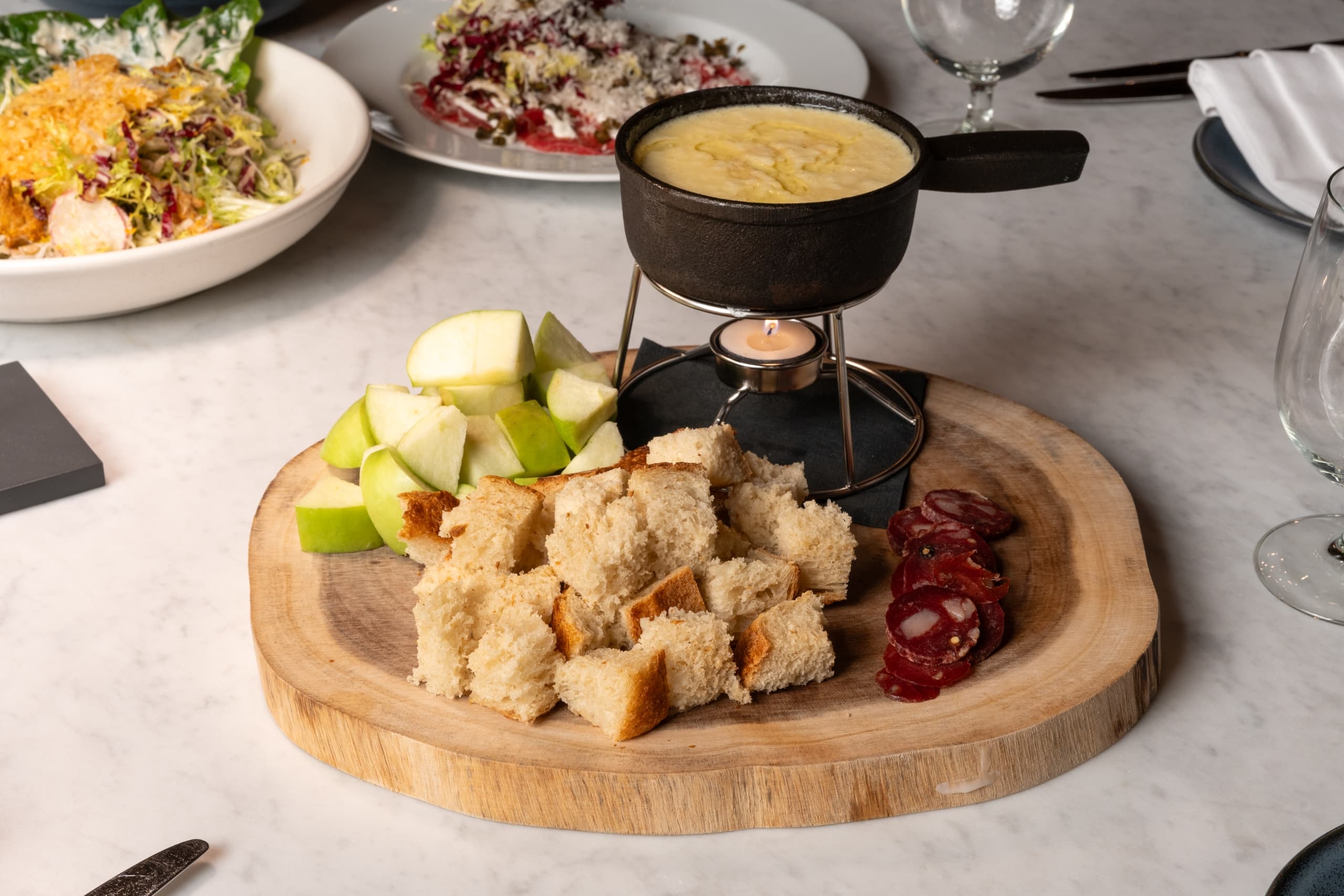 Cheese fondue and plates of salad from Snake River Sporting Club's winter dining menu