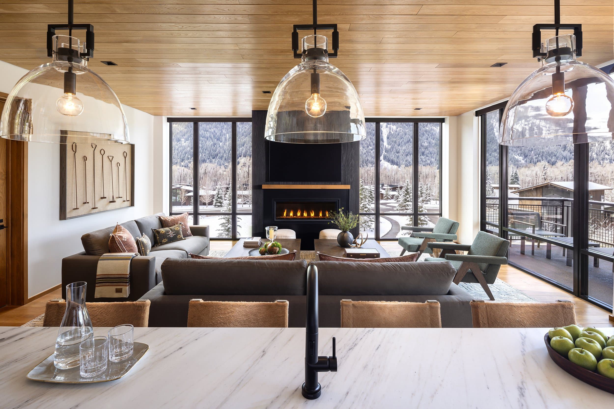 Open living room and kitchen with fireplace and snowy mountain views at Snake River Sporting Club in Jackson Hole, Wyoming