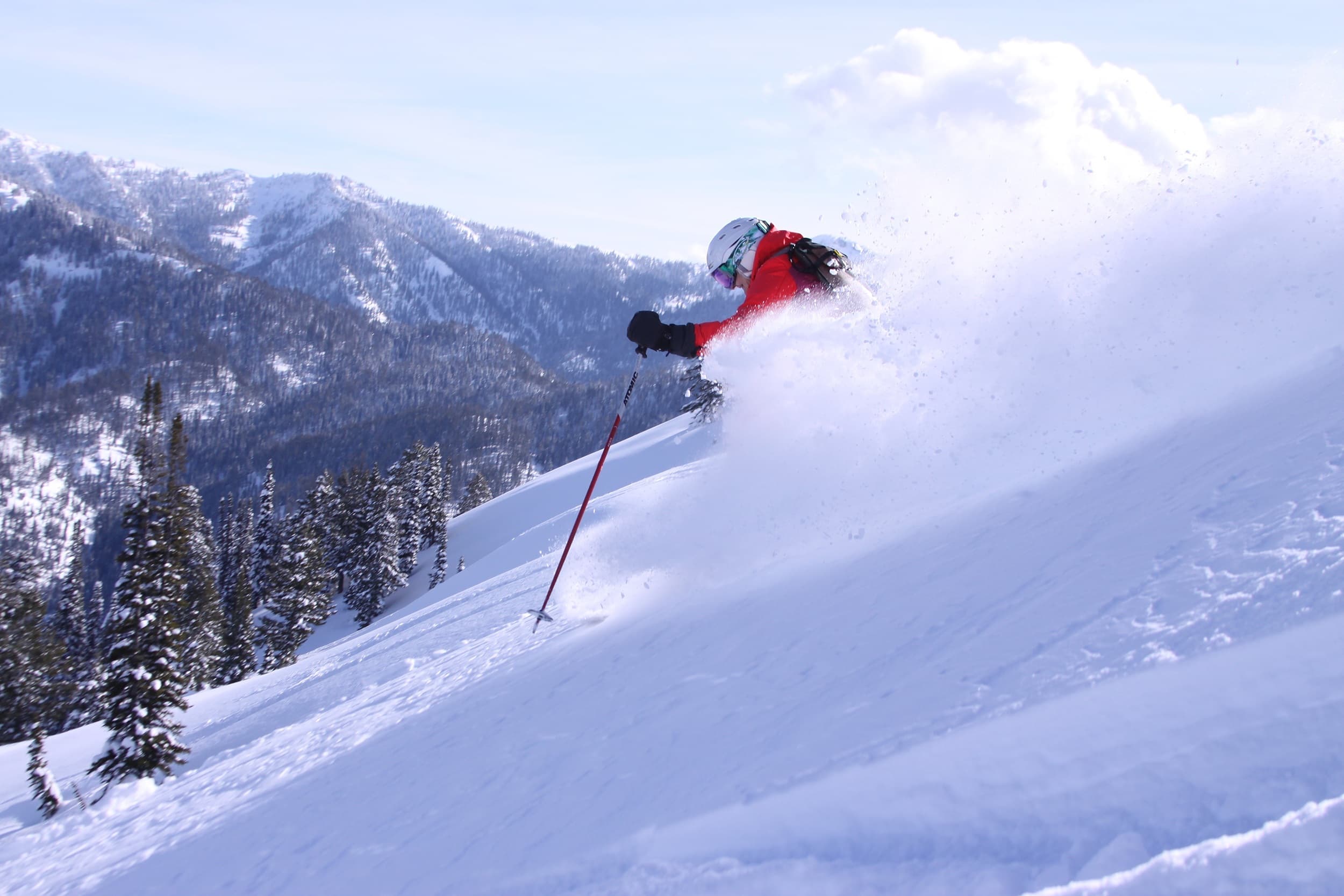 Skier carving through deep powder snow with mountain views near Snake River Sporting Club in Jackson Hole, Wyoming
